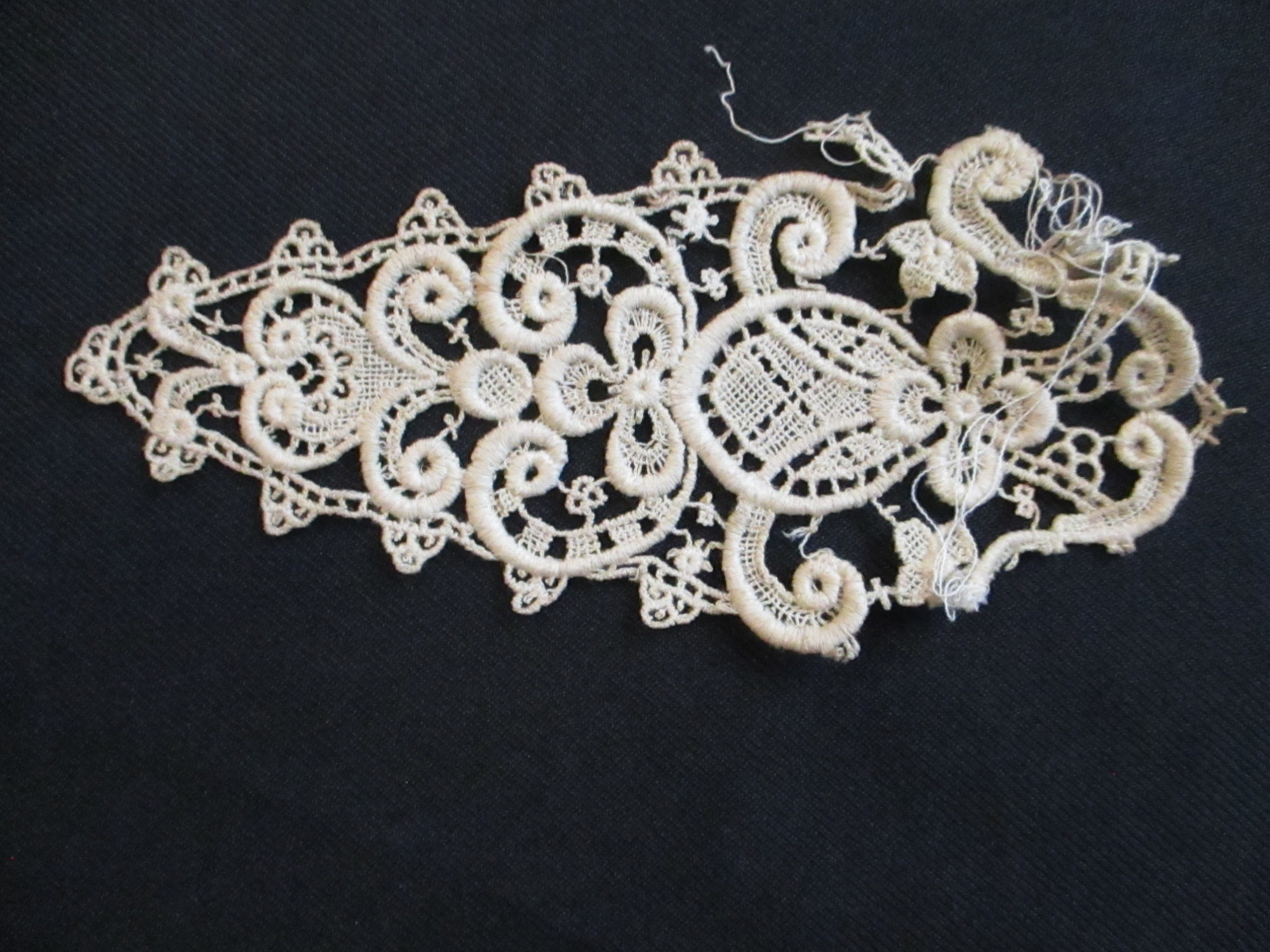 4 triangular pieces of silk lace decoration.: Triangular lace motif.