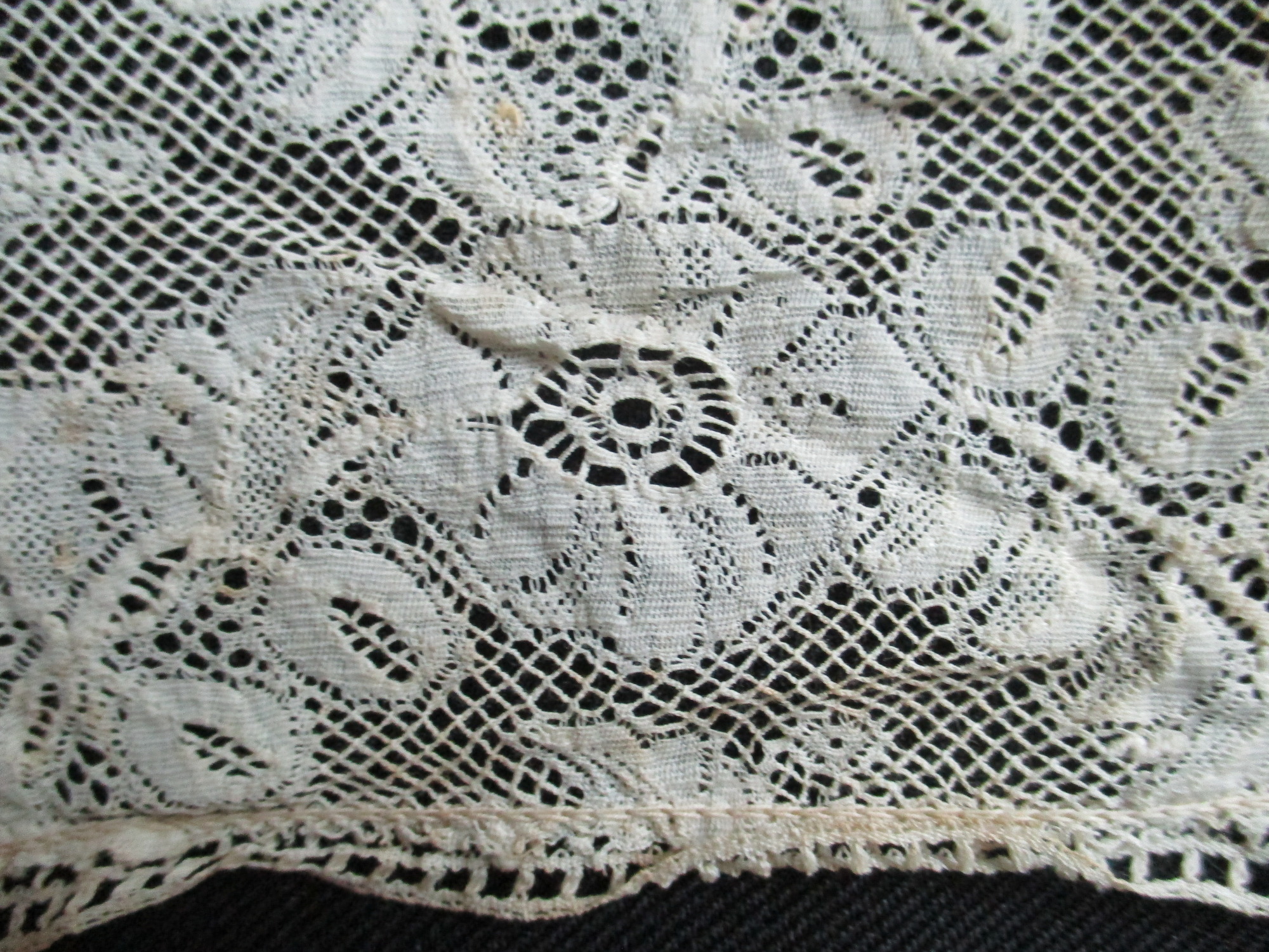 Four pieces of cream lace.: Close up detail of silk lace remnant.