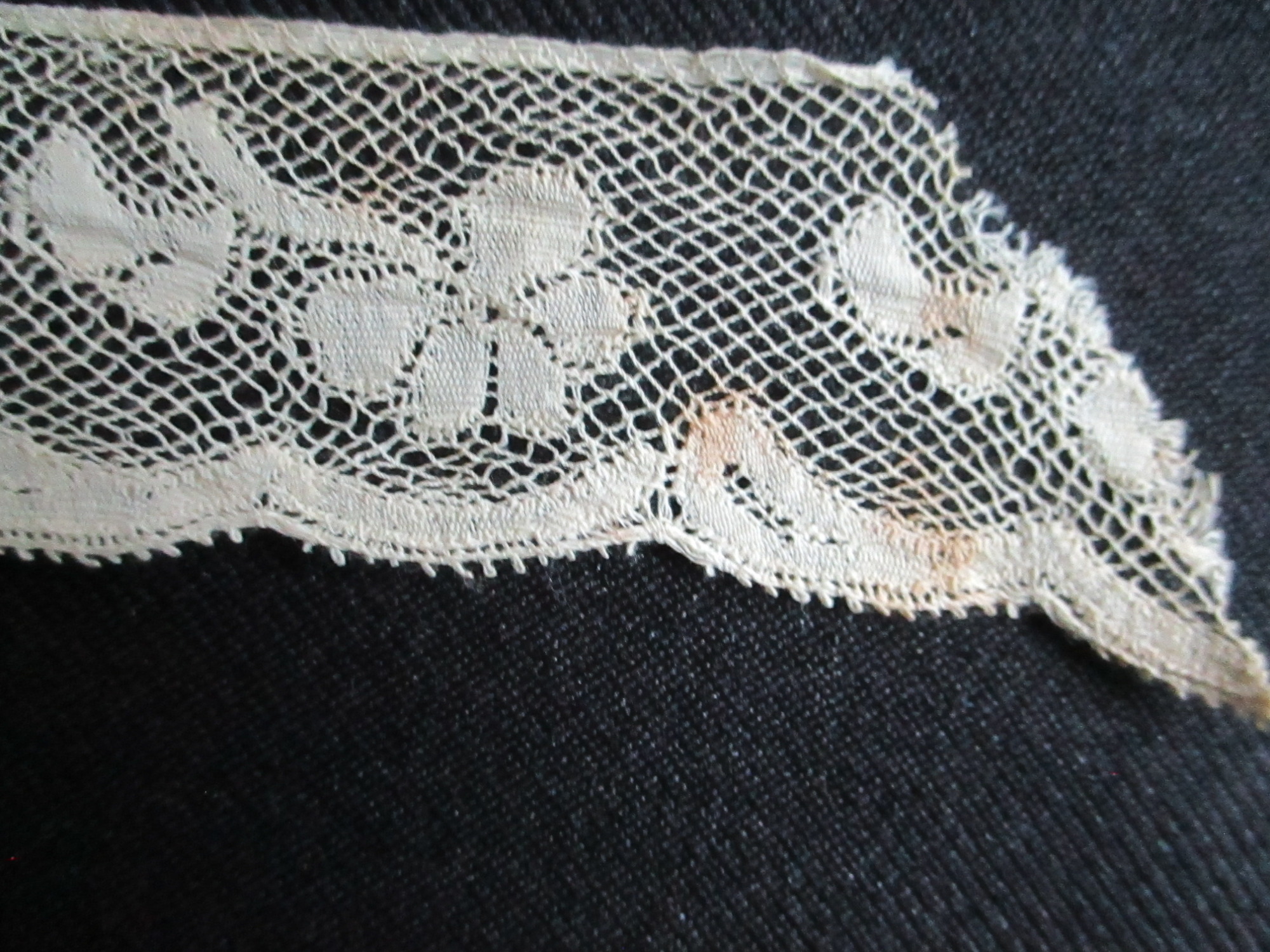 Length of folded silk lace trim.: End detail of folded cream silk lace trim. (ii)