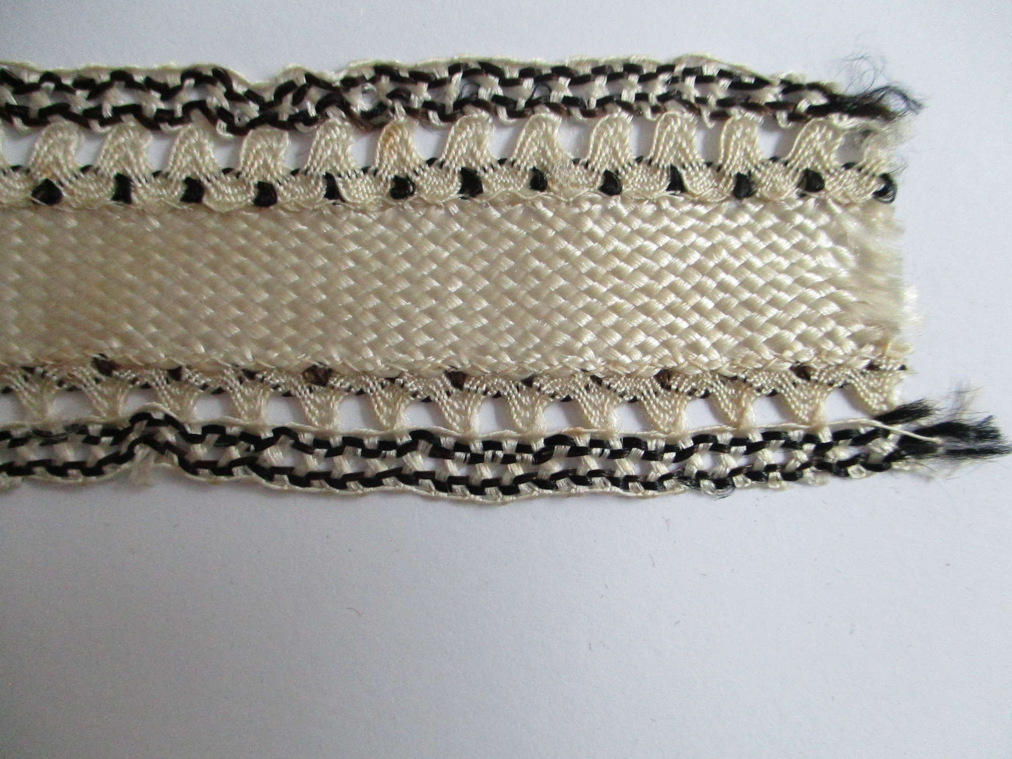 Length of silk ribbon/trim.: Detail of cream and black silk ribbon. (i)