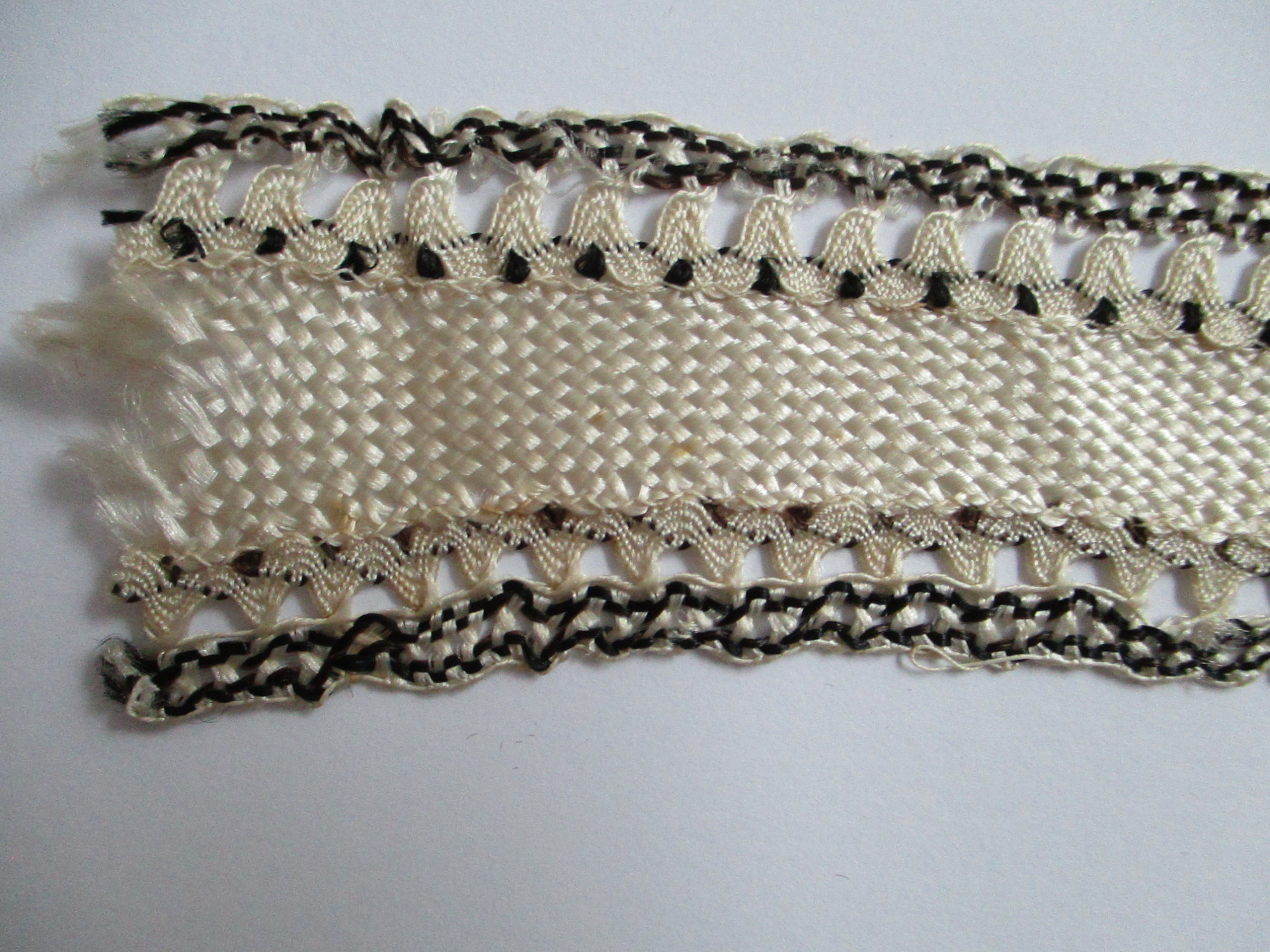 Length of silk ribbon/trim.: Detail of cream and black silk ribbon. (ii)