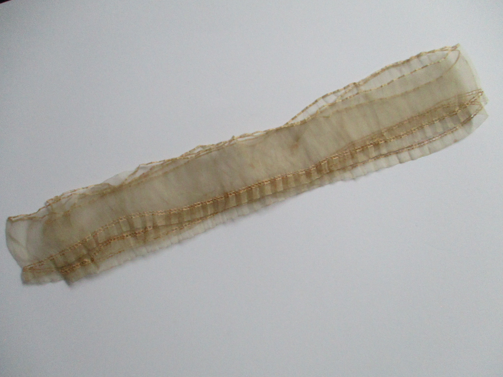 Piece of cream silk edging/trim.: Long length of cream silk ribbon/edging folded. (ii)