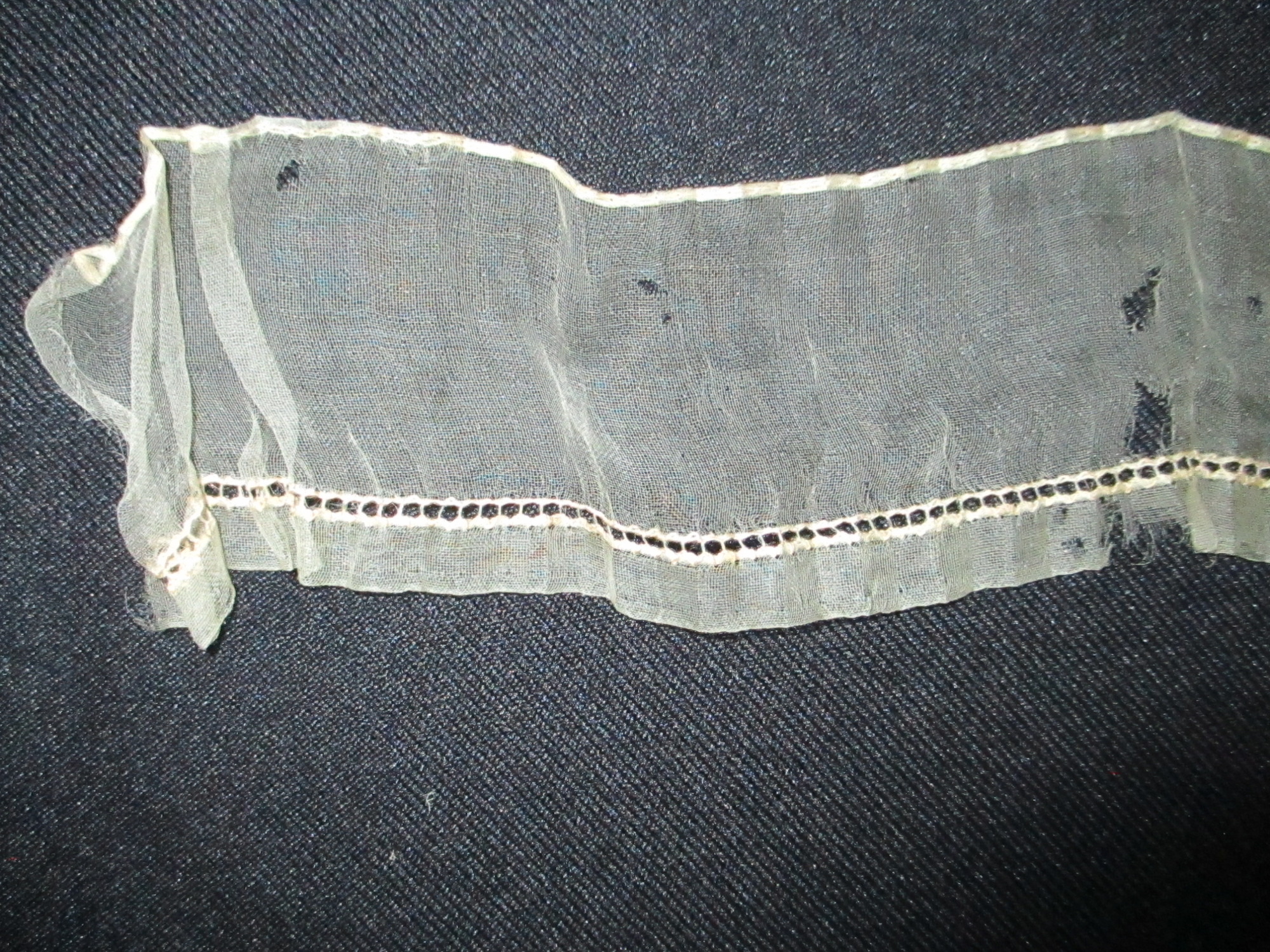 Piece of cream silk edging/trim.: Close-up of cream silk ribbon/edging. (i)