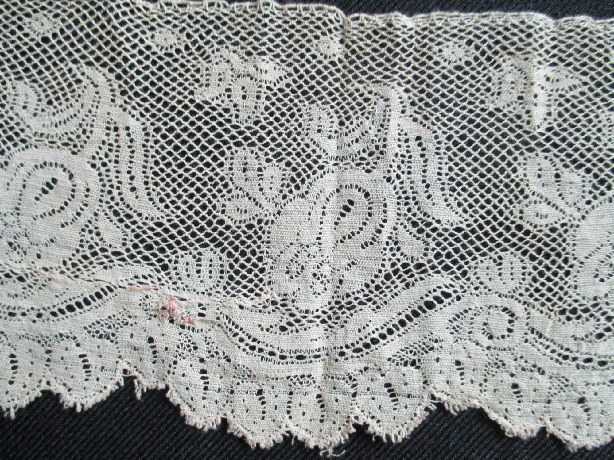 Piece of cream silk lace edging.: Close-up detail of cream silk lace edging.