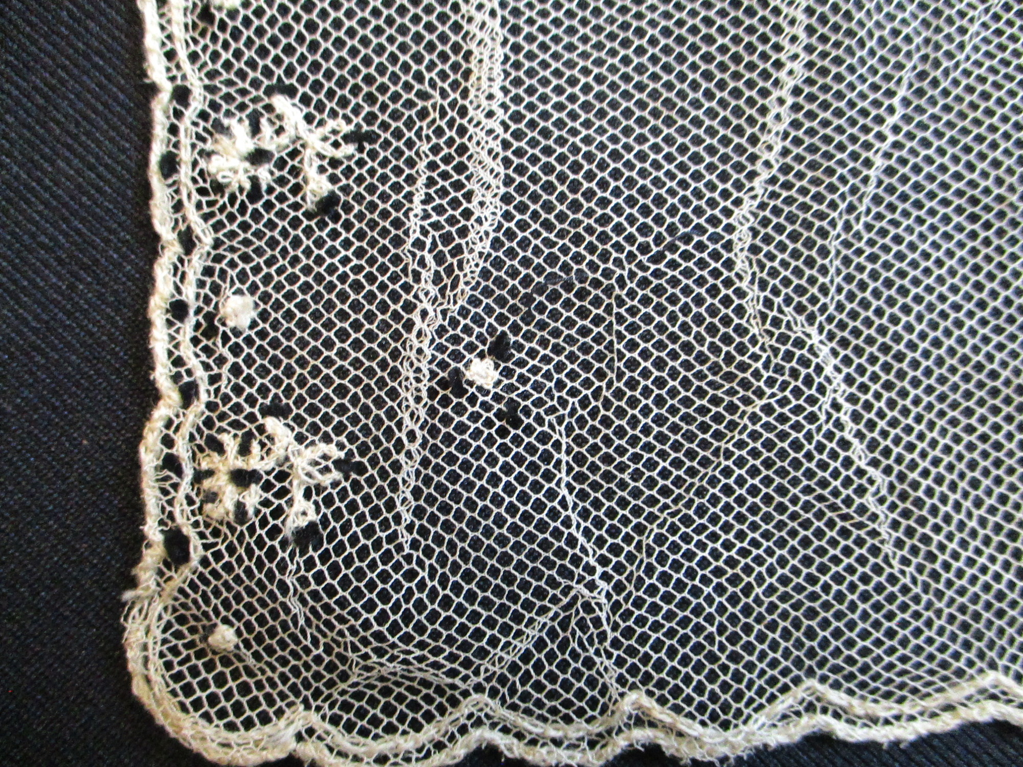 Piece of decorated cream netting.: Corner detail of cream nylon netting piece.