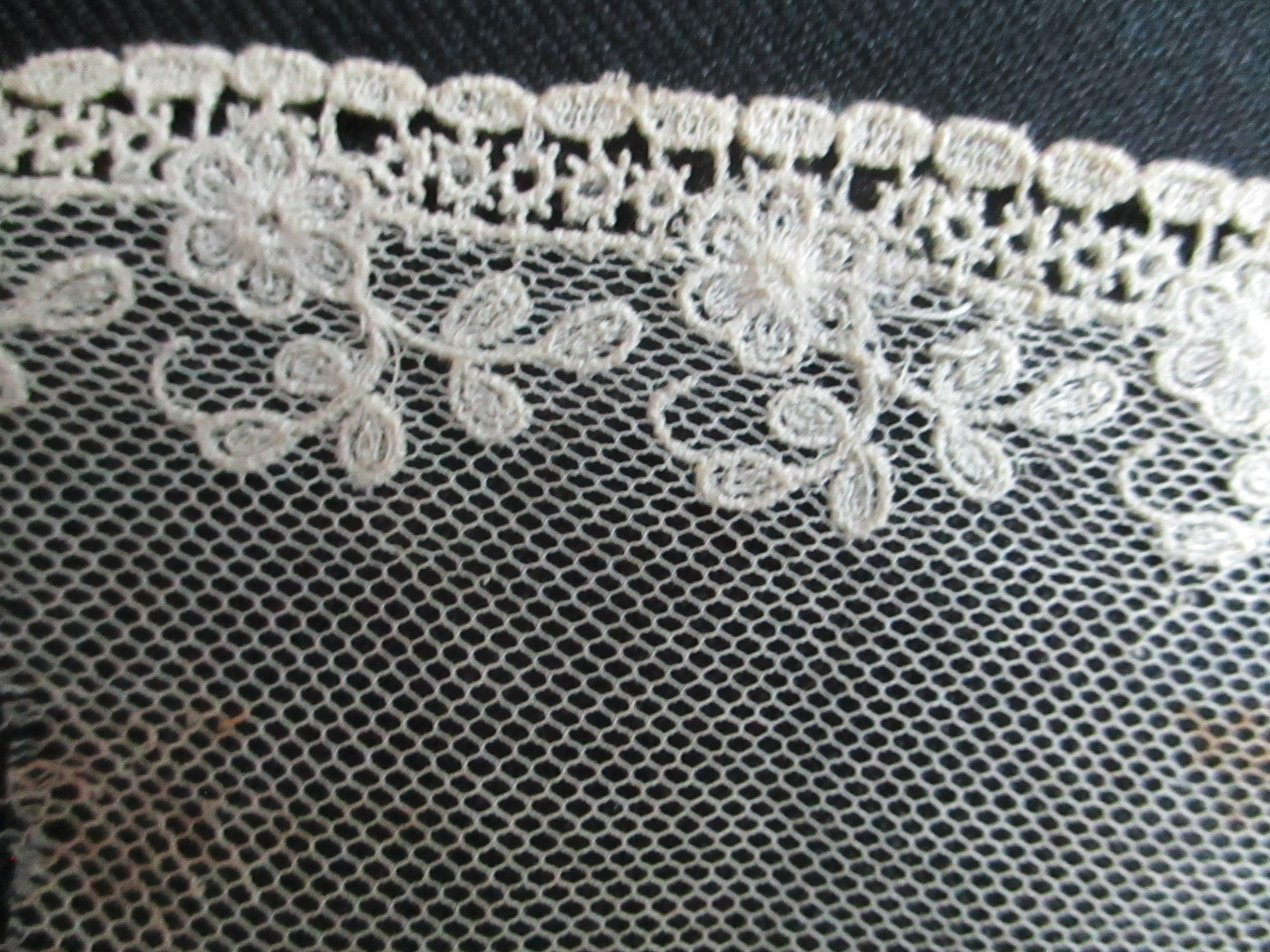 Piece of decorated nylon netting.: Close image of decoration on cream netting.