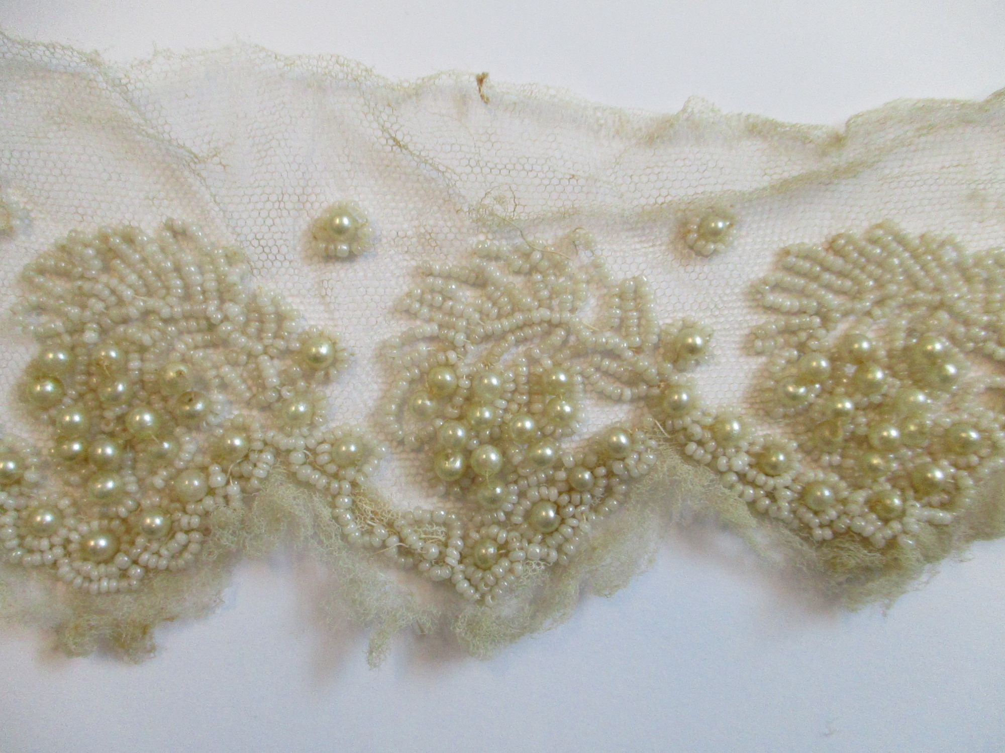Strips of heavily beaded cream netting: Beading detail on cream netting. (iii)