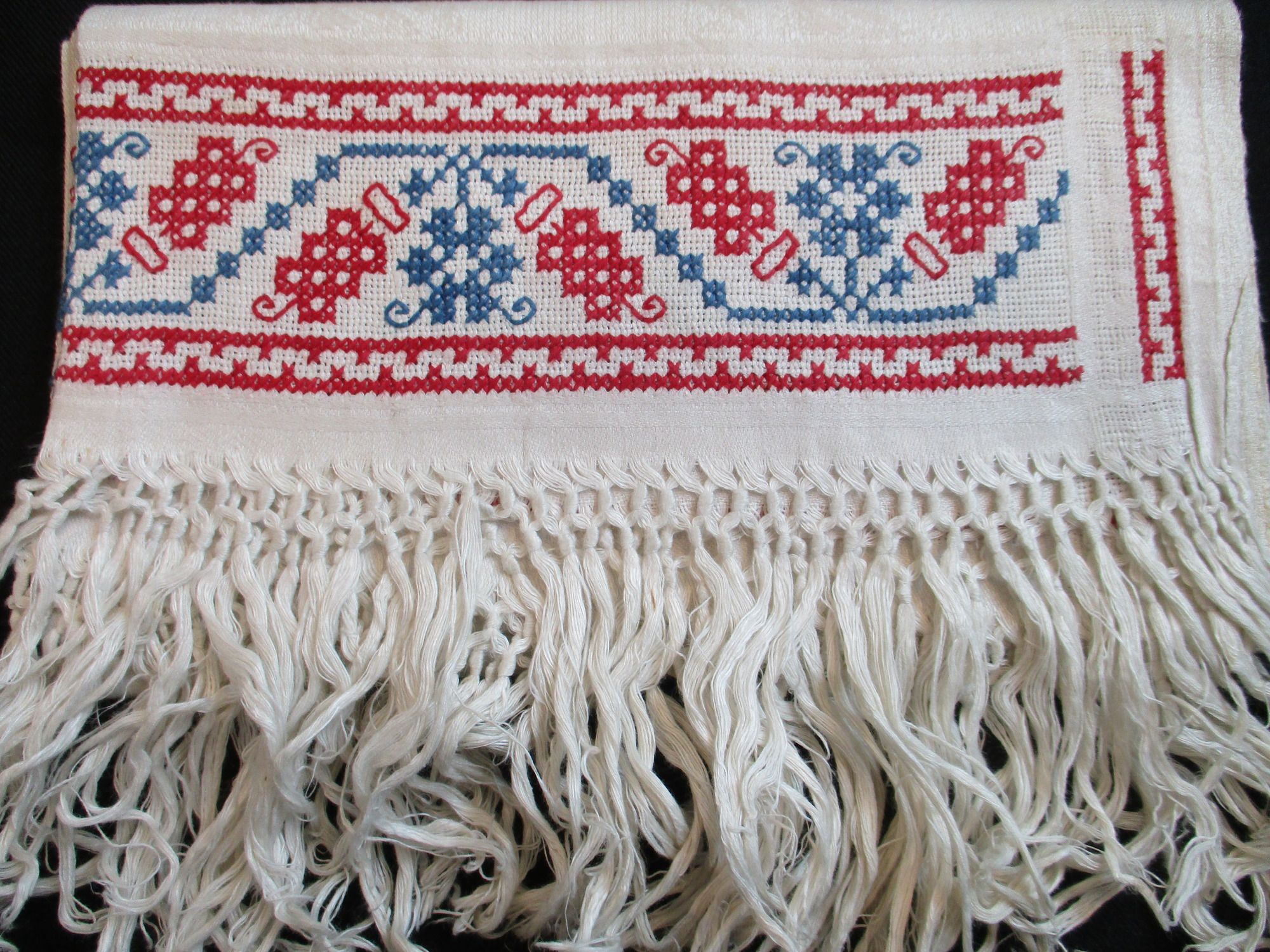 Two fringed towels: Close-up of cross-stitched design.