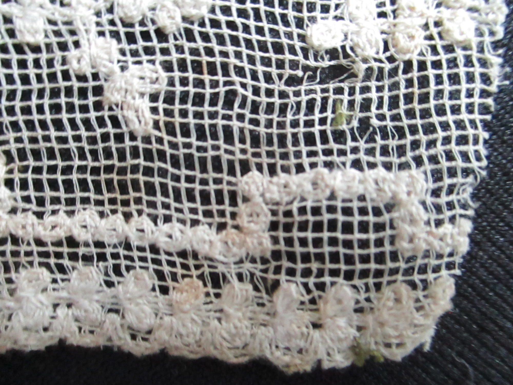 Two pieces of decorated cream netting.: Edge detail on cream lace ribbon pieces.