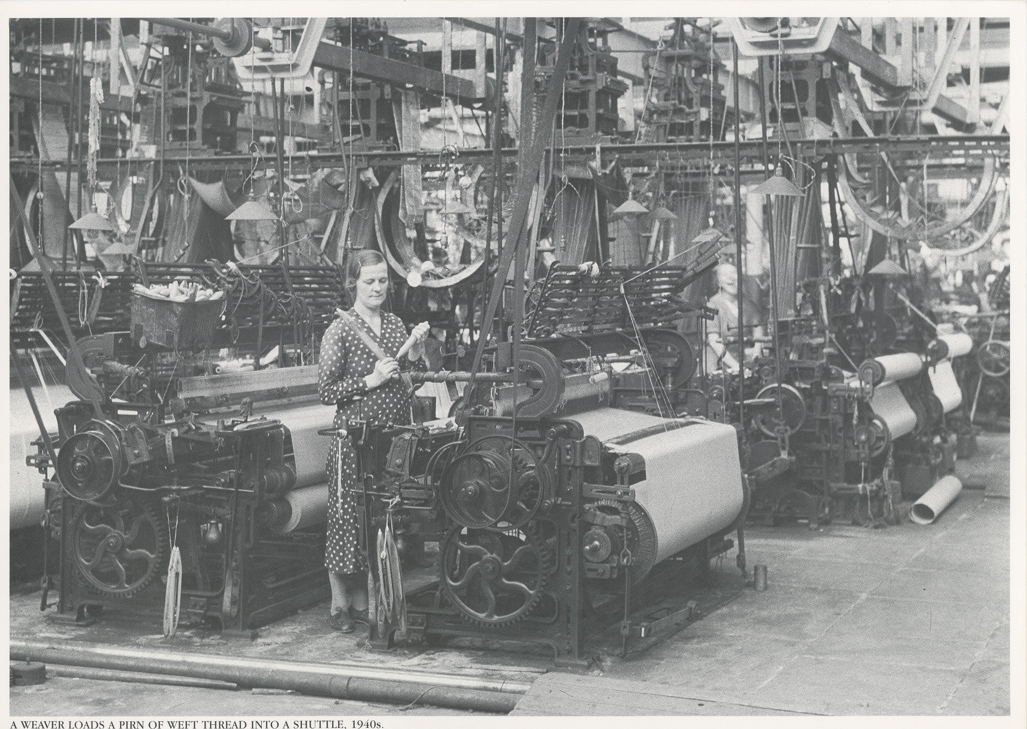A weaver loads a pirn of weft thread into a shuttle, 1940s